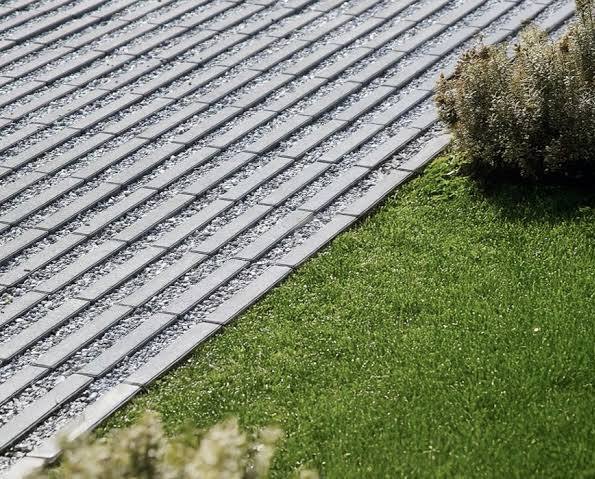 Oprit met open bestrating en steenslagvoegen naast een groene grasstrook